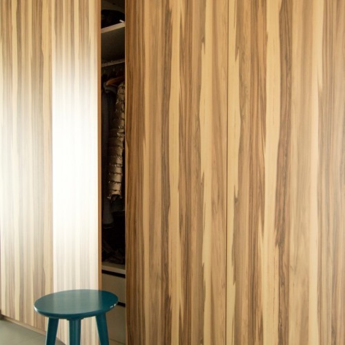 De verticale nerfrichting (Caraïbische notelaar) geeft de inkomhal nog een ruimere en hogere aanblik.  Kast-ID Asse